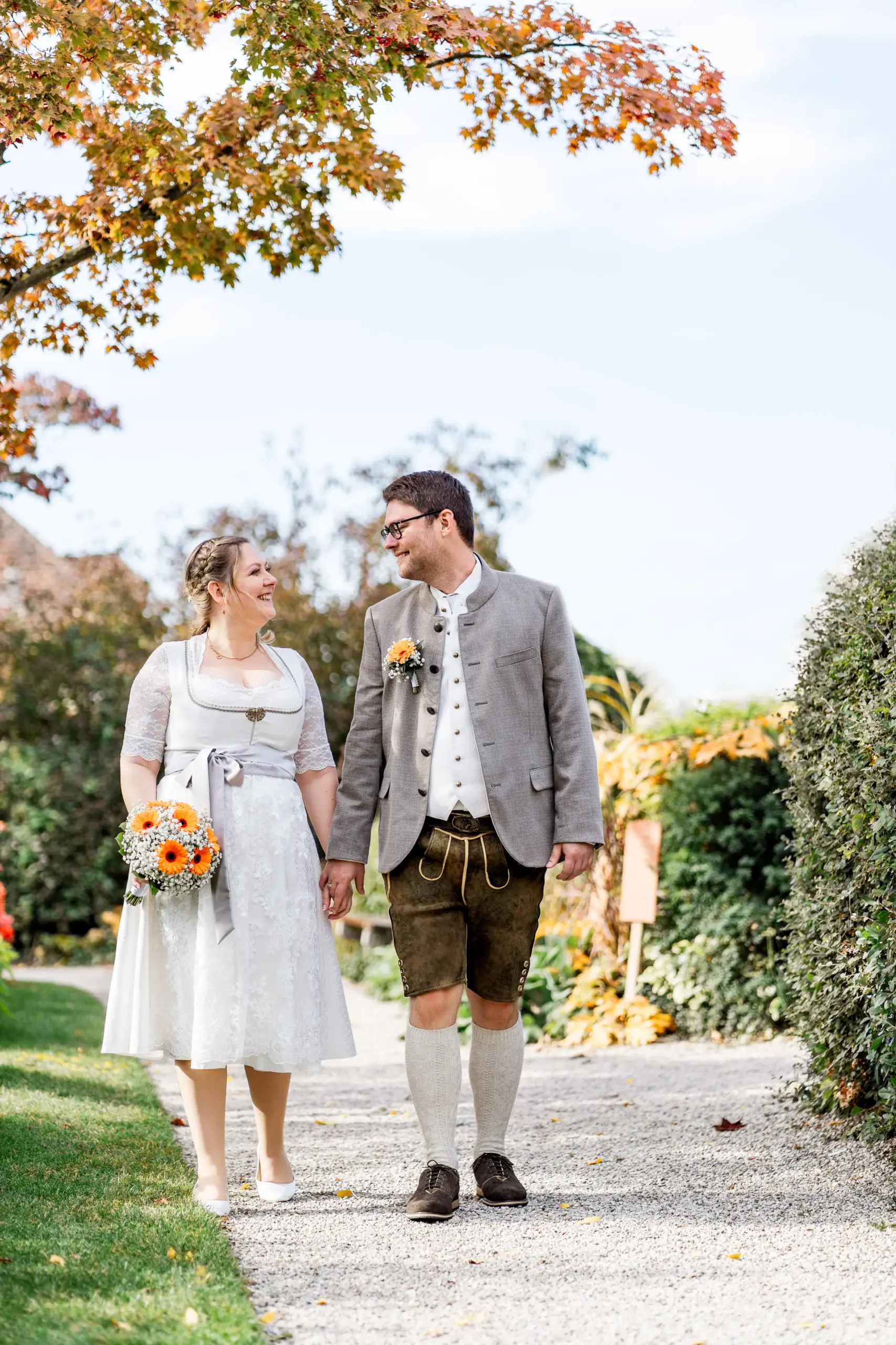 Sabrina und Markus spazieren Hand in Hand mit Brautstrauß im Literaturgarten - Martin Schinnerl Fotografie